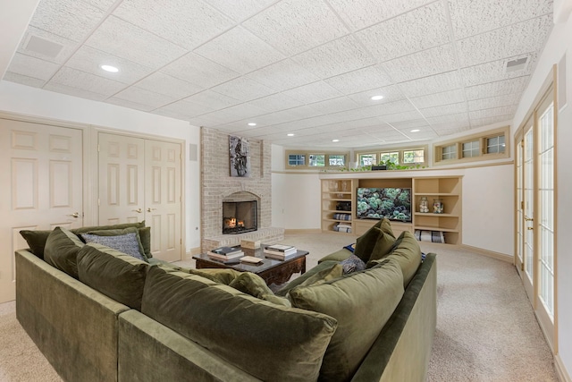 living area featuring baseboards, a fireplace, visible vents, and light colored carpet