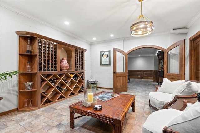 wine room with arched walkways, recessed lighting, ornamental molding, wainscoting, and stone tile flooring