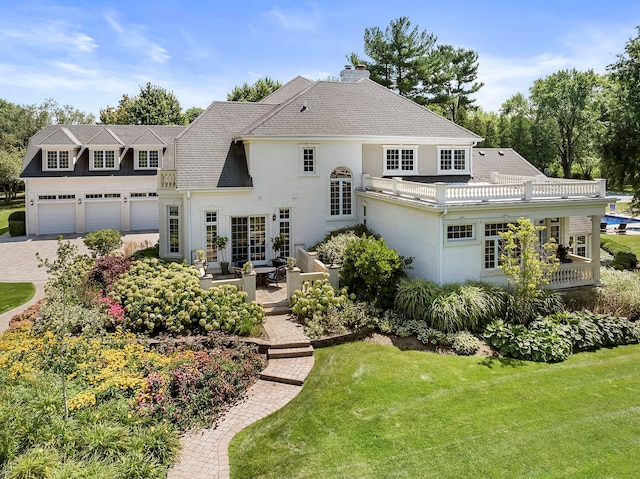 rear view of house with a garage, french doors, a lawn, and driveway