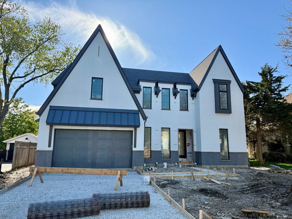 view of front of property featuring a standing seam roof, an attached garage, metal roof, a shingled roof, and fence
