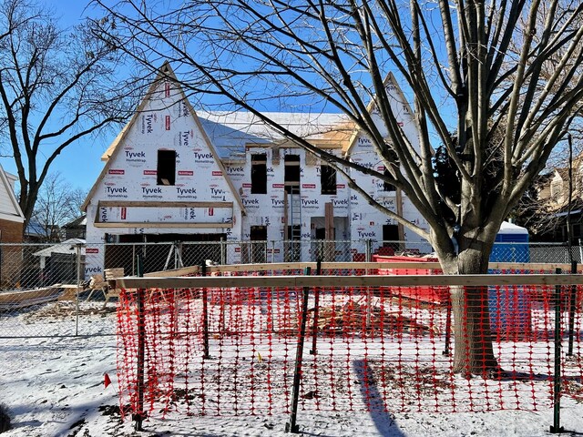 snow covered house featuring fence