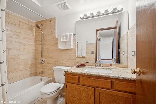 full bathroom featuring visible vents, toilet, shower / bathtub combination, vanity, and tile walls