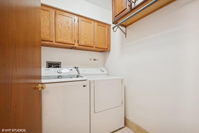 washroom featuring light tile patterned floors, washing machine and dryer, cabinet space, and baseboards