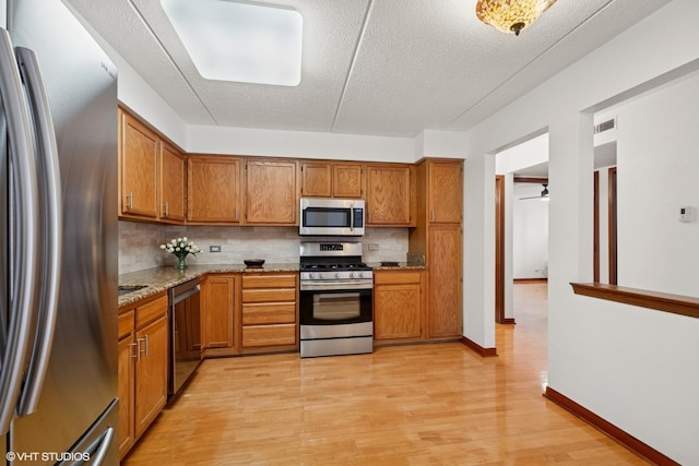 kitchen with stainless steel appliances, brown cabinetry, and backsplash