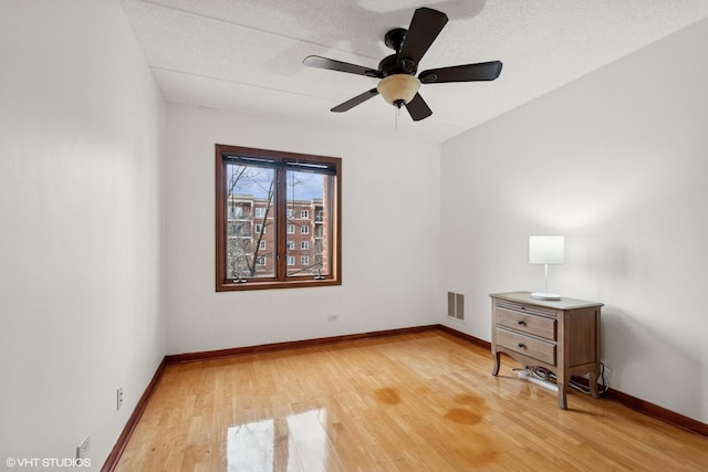 spare room with ceiling fan, a textured ceiling, visible vents, baseboards, and light wood-style floors