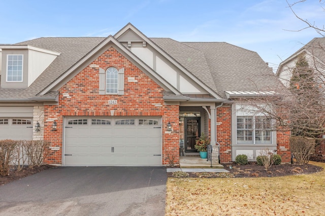 view of front of home with roof with shingles, brick siding, and driveway