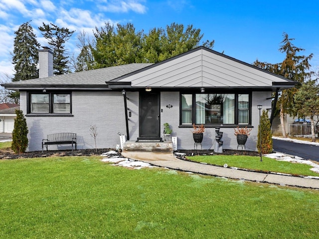 view of front facade featuring brick siding, a chimney, and a front lawn