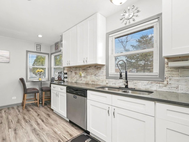 kitchen featuring a sink, white cabinetry, light wood-type flooring, dishwasher, and dark countertops