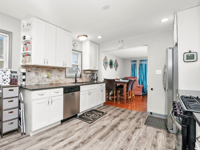 kitchen featuring stainless steel appliances, dark countertops, white cabinets, and open shelves