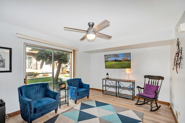 living area featuring a ceiling fan, light wood-style flooring, and baseboards