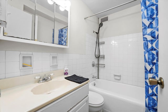 full bath with visible vents, shower / tub combo with curtain, toilet, tile walls, and vanity