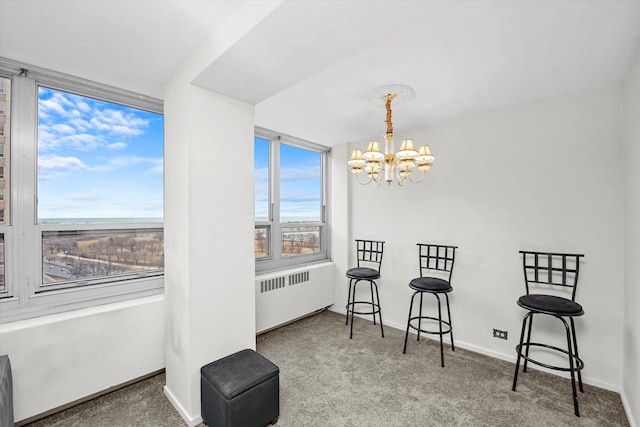 living area featuring baseboards, carpet floors, radiator, and an inviting chandelier