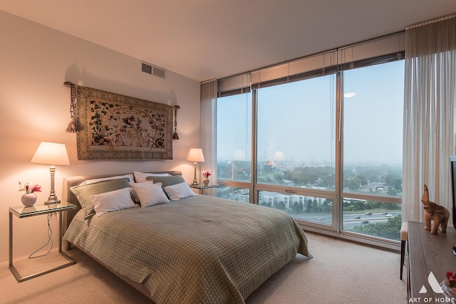 bedroom with visible vents, multiple windows, carpet, and floor to ceiling windows