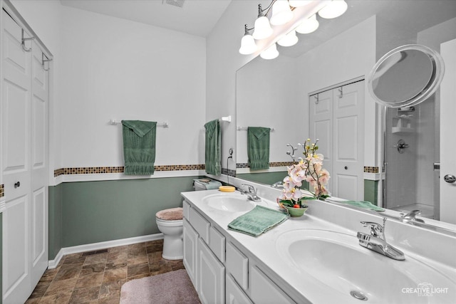 bathroom with toilet, double vanity, a sink, and visible vents