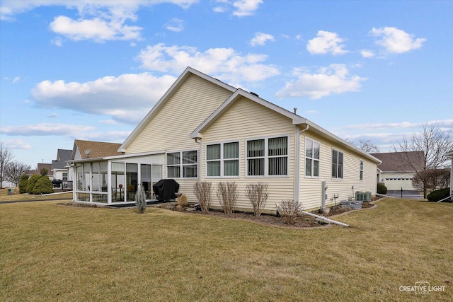 rear view of house with a sunroom, central AC, and a yard