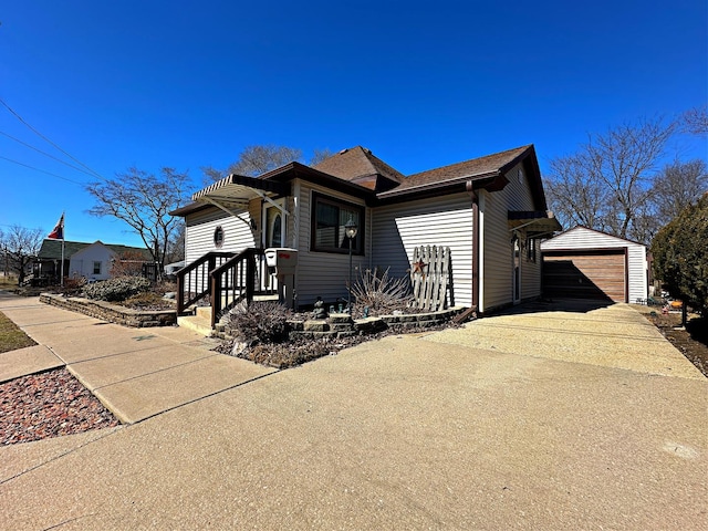 view of front facade featuring concrete driveway, an outbuilding, and a garage