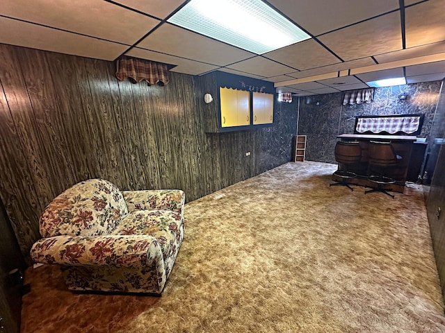 interior space with a paneled ceiling, wood walls, a bar, and carpet floors