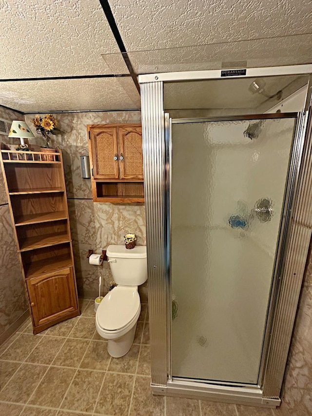 bathroom with a shower stall, toilet, and tile patterned floors