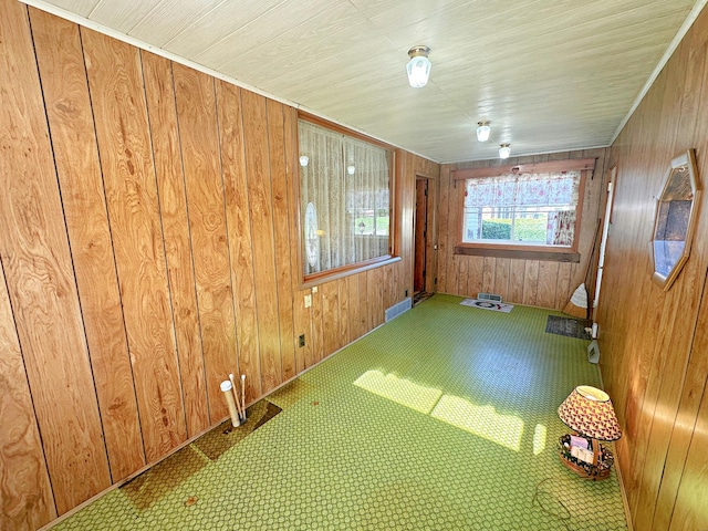 spare room featuring wood walls, visible vents, and baseboards