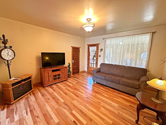 living area featuring baseboards and light wood finished floors