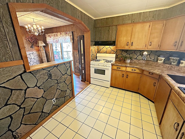 kitchen featuring white gas range oven, light countertops, crown molding, a chandelier, and exhaust hood