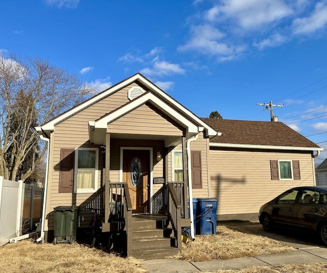 view of front of property featuring roof with shingles and fence