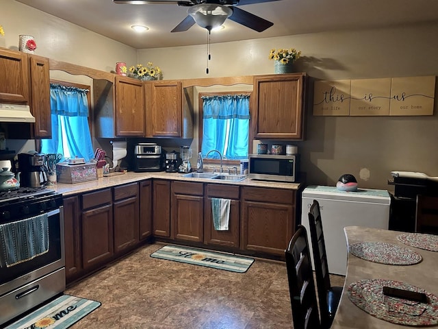 kitchen featuring a wealth of natural light, light countertops, appliances with stainless steel finishes, a sink, and under cabinet range hood