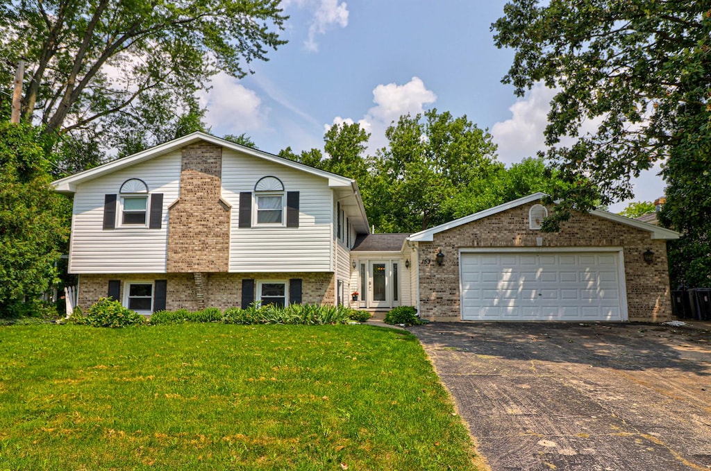 tri-level home featuring a garage, driveway, and brick siding