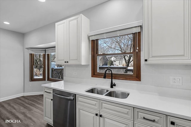 kitchen with light countertops, stainless steel dishwasher, a sink, and a healthy amount of sunlight