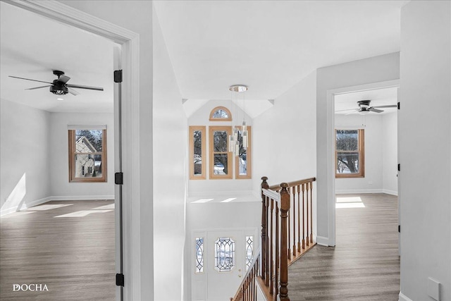 hall featuring baseboards, an upstairs landing, and wood finished floors