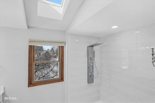 full bathroom with vaulted ceiling with skylight and a tile shower