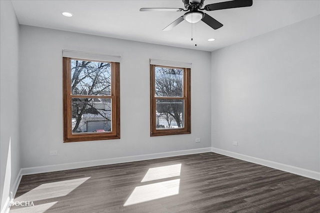 empty room featuring dark wood-style floors, plenty of natural light, and baseboards