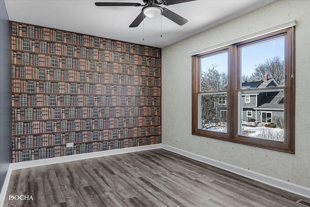 spare room with a ceiling fan, visible vents, baseboards, and wood finished floors