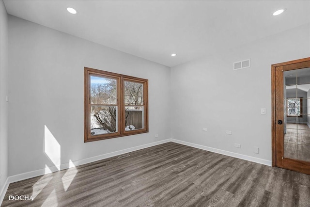 empty room with dark wood-style floors, baseboards, visible vents, and recessed lighting