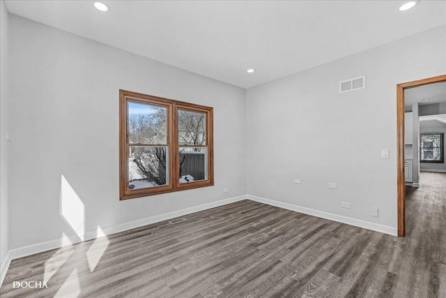 spare room featuring baseboards, visible vents, and dark wood finished floors