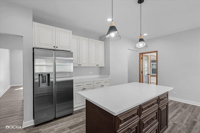 kitchen with dark wood-style floors, light countertops, stainless steel fridge with ice dispenser, and white cabinetry