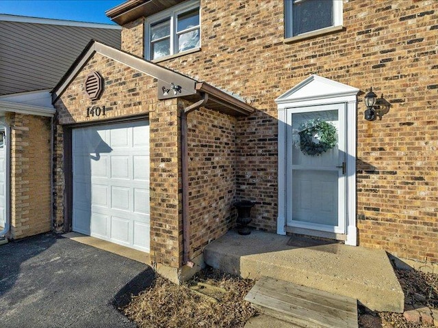 entrance to property featuring aphalt driveway and brick siding