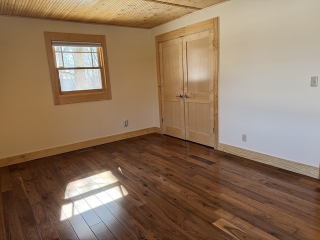 unfurnished bedroom featuring a closet, dark wood finished floors, wood ceiling, and baseboards