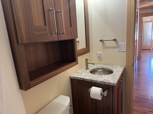 bathroom with wood finished floors, vanity, and toilet