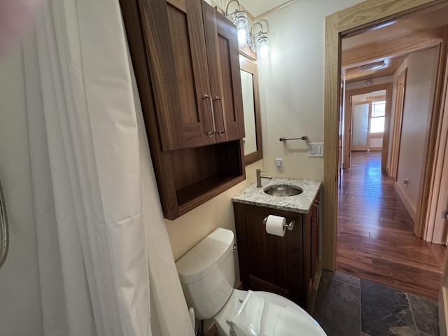 bathroom featuring wood finished floors, vanity, toilet, and baseboards