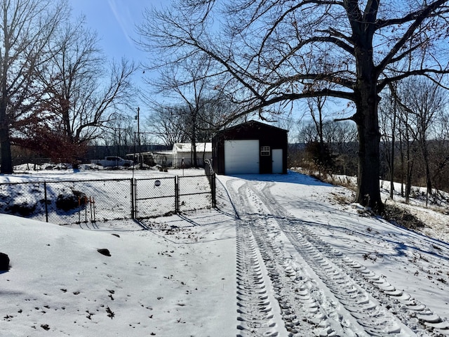 yard layered in snow featuring a garage, fence, and an outdoor structure