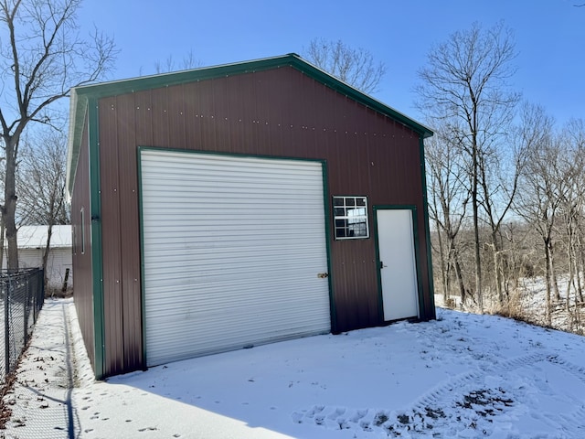 snow covered structure featuring an outdoor structure and fence