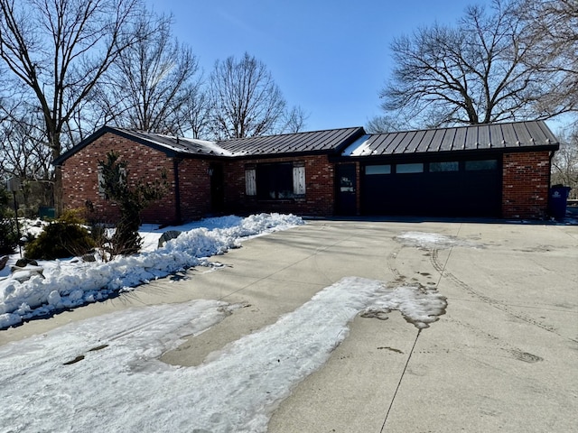 view of front of property with a garage, concrete driveway, metal roof, a standing seam roof, and brick siding