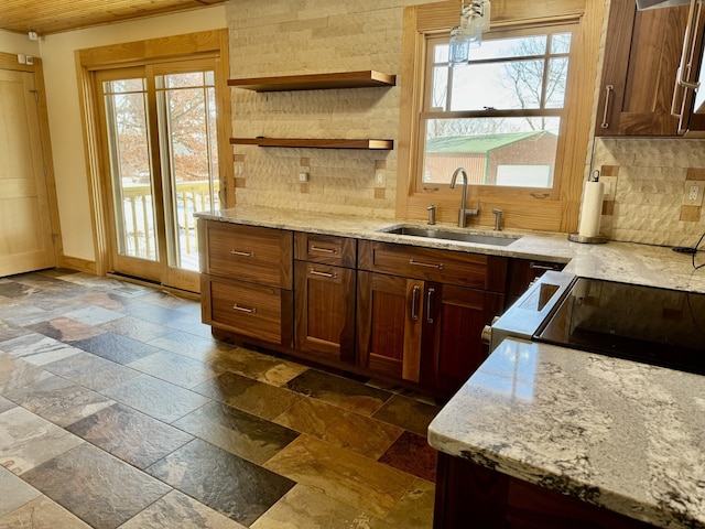 kitchen with a sink, light stone countertops, stone tile flooring, open shelves, and backsplash