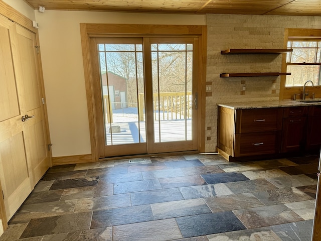 doorway featuring wooden ceiling, a sink, stone tile flooring, and baseboards