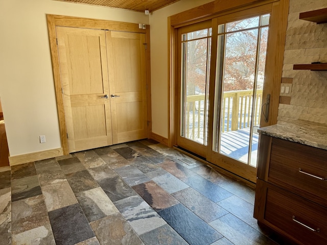 entryway with baseboards, plenty of natural light, visible vents, and stone tile floors