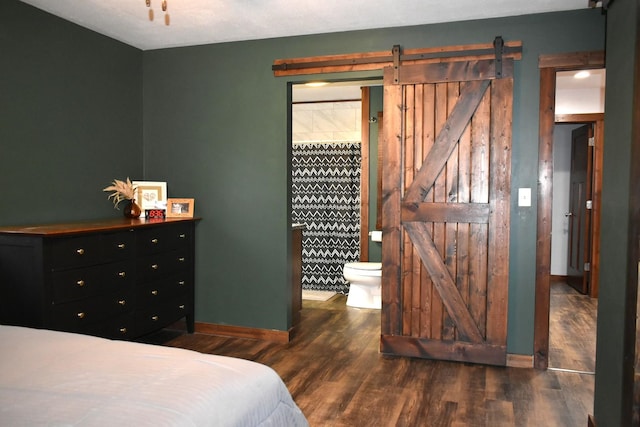 bedroom featuring a barn door, baseboards, and wood finished floors