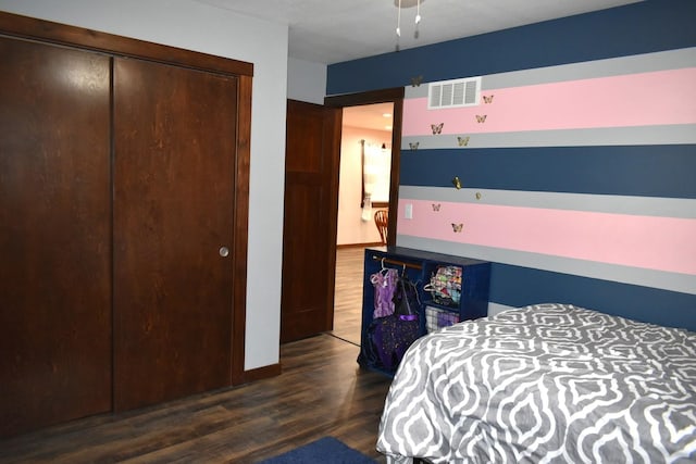 bedroom with a closet, wood finished floors, visible vents, and baseboards