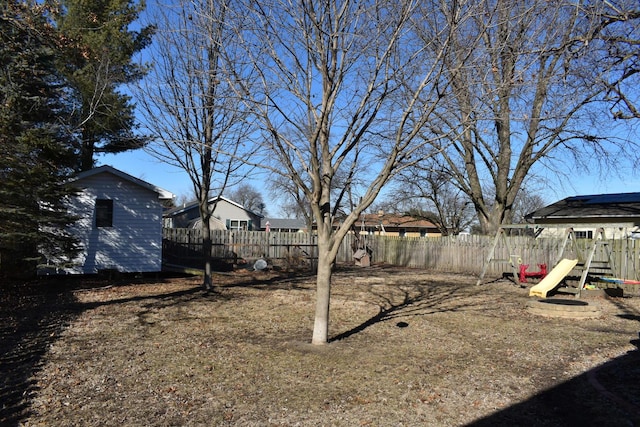 view of yard featuring a storage unit, fence, a playground, and an outbuilding