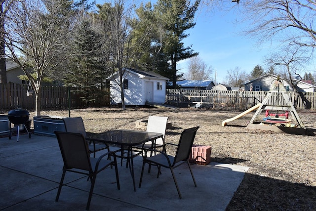 view of patio with a storage shed, a fenced backyard, a grill, an outdoor structure, and outdoor dining space